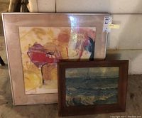 Both framed art pieces leaning against basement wall