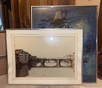 Two framed wall art prints stacked with cityscape in front of abstract floral, displayed for lot contents.