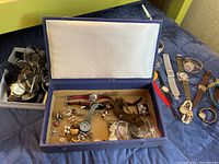 Full view of box containing various watches and costume jewelry with some watches laid out around it.