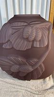 Front view of purple frosted glass vase showing raised floral and leaf design on rounded body.