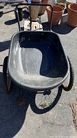 Front view of black plastic tub garden cart with metal frame and wheels.