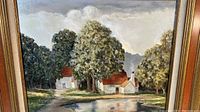 Framed vintage painting depicting two farmhouses in a rural setting with trees and water reflections.