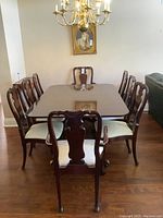 Full set showing large rectangular double pedestal dining table on wheels surrounded by 8 matching carved chairs with cushioned seats