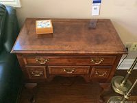 Front view of Henredon desk showing polished wood finish, clawed feet, and four drawers with metal handles.