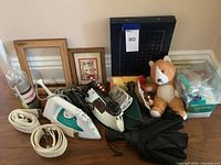 Wide shot showing all items in the lot including irons, fitness watch, photo frames, photo albums, umbrella, and plush toy.