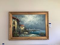 Front view of framed oil painting showing Venice village scene with sky and water body.