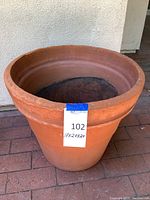 Side view of large clay planter pot showing size and shape, tag indicating dimensions 17x20x20