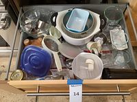 Drawer with assortment of kitchen items including bowls, measuring cups, containers, colander, and utensils.