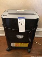 Side/front angle picture of the shredder on caster wheels, showing the full body and power cord.