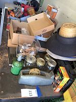 Overview of workbench top showing various boxed tools, mini clothes presser, mason jars, flashlight, hats, and miscellaneous household items.