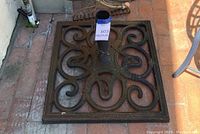 Top-down view of square metal umbrella stand base with decorative scroll designs
