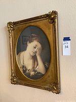 Framed Victorian style woman art print hanging on wall with decorative corner and edge detailing on gold frame