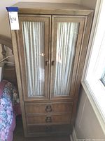 Front view of wooden wardrobe mini dresser with two vertical glass flowered panel doors and three drawers below.