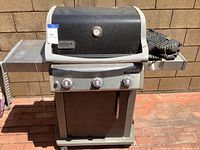 Front view of Weber Spirit propane BBQ grill with closed lid, showing three control knobs, foldable side shelves, and built-in analog thermometer.
