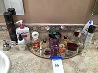 Photo of women's perfume bottles, lotions, decorative vase and mirror on bathroom counter