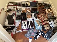 Overview of the lot showing women's shoes in boxes, spread on a hardwood floor. Includes boots, sandals, dress shoes, and tennis shoes.
