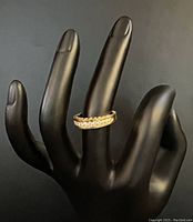Black mannequin hand displaying ring facing forward, top view showing diamond row.