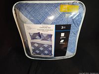 Front of the sealed comforter set packaging showing blue and white reversible design and included pieces