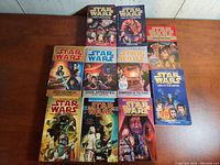 Top view of 16 Star Wars novels arranged on a wooden surface, showing covers and titles.