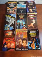Photo showing 9 Star Trek paperback novels in good condition with various covers featuring iconic Star Trek images and characters.