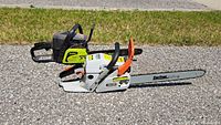 Two chainsaws side by side on pavement