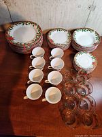 Full set arranged on table including plates, bowls, cups, saucers, and glass tumblers.