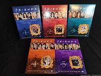 First five seasons of Friends DVD collection with individual colorful cover art showing main cast members and framed group photos.
