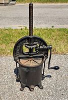Front view of Enterprise cast iron fruit press showing top arch with manufacturer name, screw mechanism, and barrel.