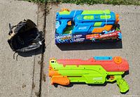 Two large water blasters and a black and tan baseball glove displayed outdoors.
