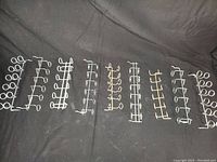 Nine metal pegboard tool holder strips laid out on a black surface