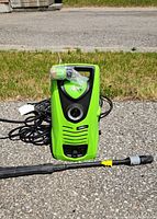 Photo of green Ultimate X pressure washer with 1500 PSI rating, hose and spray wand attached, placed on pavement outdoors.