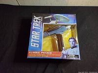 Star Trek Classic Phaser toy in original sealed box with detailed graphics, showcasing the toy in blue and gray colors.