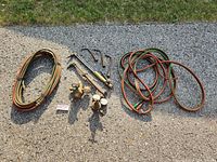 Photo showing all welding accessories laid out on pavement including hoses, torch handles, gauges, and tips.