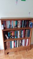 Front view of the wooden three-shelf bookcase filled with books.