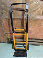 Full front view of the adjustable cart dolly showing yellow and black frame with the wheels and loading platform.