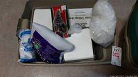 All items displayed inside beige plastic bin, including original packaging for snow fabric and drape, and wrapped items.