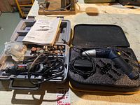 Dremel MultiPro rotary tool with its attachments, manual, and electric Mastercraft screwdriver with bits and cases on a workbench.