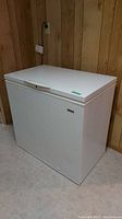 Full view of white Kenmore chest freezer showing front and left side with lid closed.