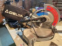 Full view of the Delta 10 inch compound mitre saw showing dust collection bag and saw base.