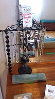 Black metal jewellery stand with multiple necklaces and bracelets displayed, showing the variety of items and overall setup.