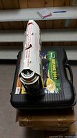 Top view of the four-pack of silver and orange Home Butane fuel canisters inside a box on top of carrying case.