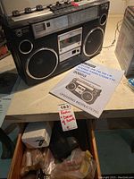 Photo of Sears stereo radio cassette recorder with instruction manual and partially open drawer showing dowels and other items