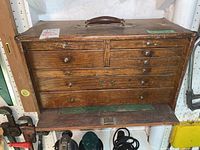 Front view of oak-finished wooden tool chest with leather handle and eight drawers