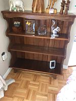 Full front view of the wooden shelf showing its overall shape, multiple shelves, and contents currently on display (not included in sale).