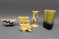 Five McCOY and HULL USA ceramic pottery pieces displayed side by side on gray background showing various shapes, colors, and decoration.