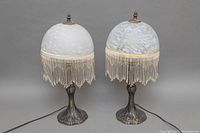 Front view of the pair of Art Deco style boudoir lamps showing frosted dome glass shades with beaded fringe and ornate bases.