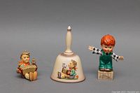 Three items displayed: two figurines and one decorative bell.