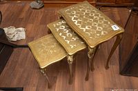Set of three wooden 1950s Florentine nesting tables with gold finish and visible wear, showing original Italy stickers.