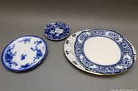 Four porcelain serving pieces arranged on a gray surface showing size differences and blue patterned decoration.