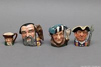 Front view of the four Toby mugs showing detailed character heads and colors.